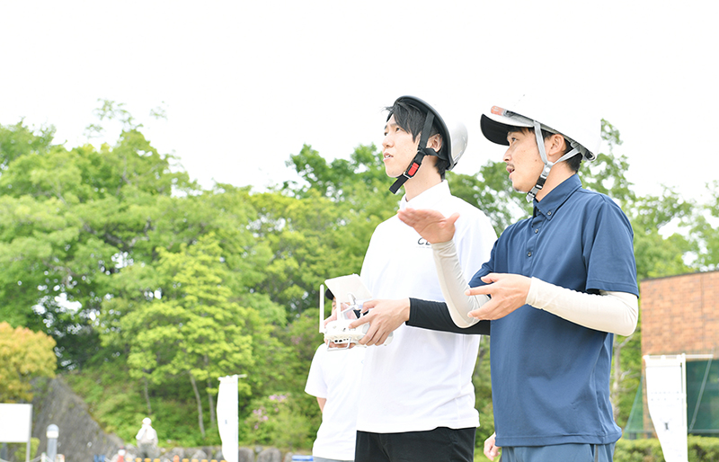 ドローン操縦の指導を受ける教師と生徒